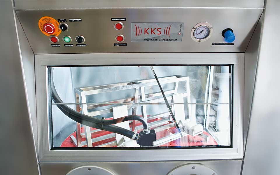Detailbild des grossen Sichtfensters inklusive Scheibenwischer der Nassstrahlanlage Typ KKS-NI für das Strahlen von Oberflächen aus der Industrie.